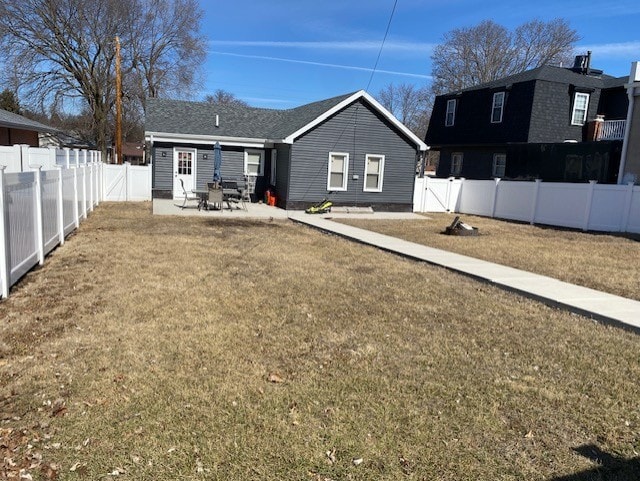 rear view of property featuring a patio, a lawn, and a fenced backyard