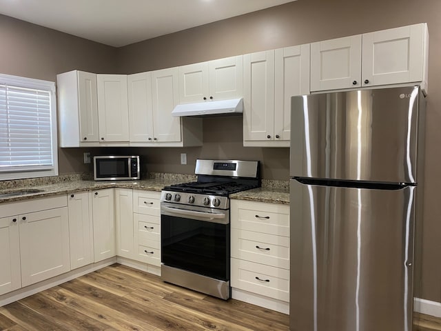 225 W Dakota St, Spring Valley, IL 61362 - kitchen with appliances with stainless steel finishes, under cabinet range hood, wood finished floors, and white cabinets
