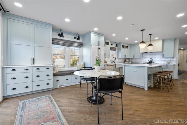 kitchen with tasteful backsplash, light countertops, a kitchen island, wood finished floors, and high end refrigerator