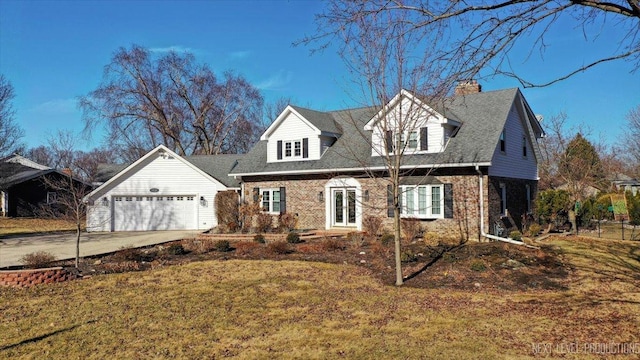 new england style home with an attached garage, brick siding, concrete driveway, french doors, and a front lawn