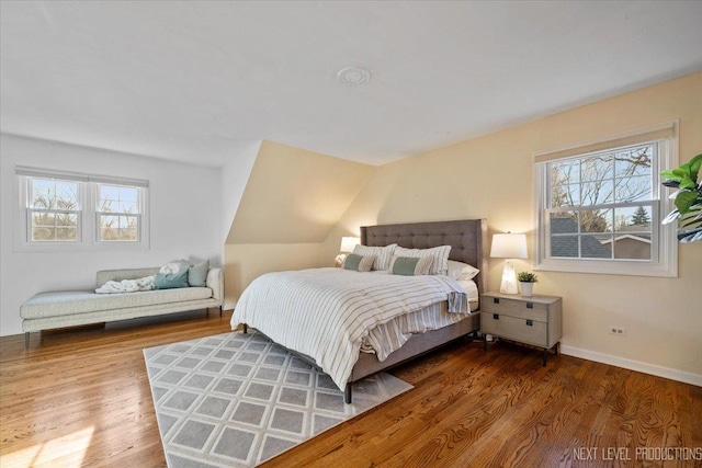 bedroom featuring lofted ceiling, baseboards, and wood finished floors