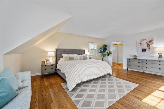 bedroom featuring lofted ceiling, baseboards, and wood finished floors