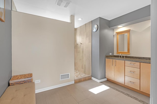 bathroom with visible vents, a walk in shower, vanity, and baseboards