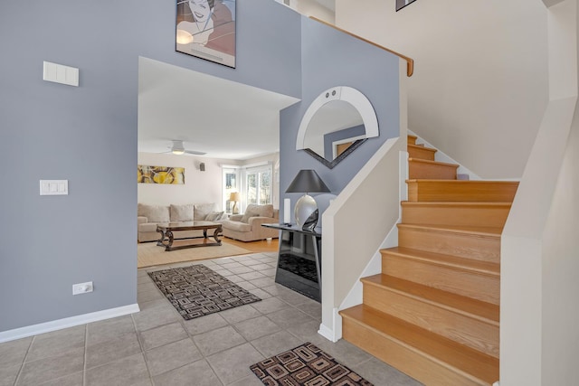 tiled entrance foyer featuring stairway, baseboards, and ceiling fan