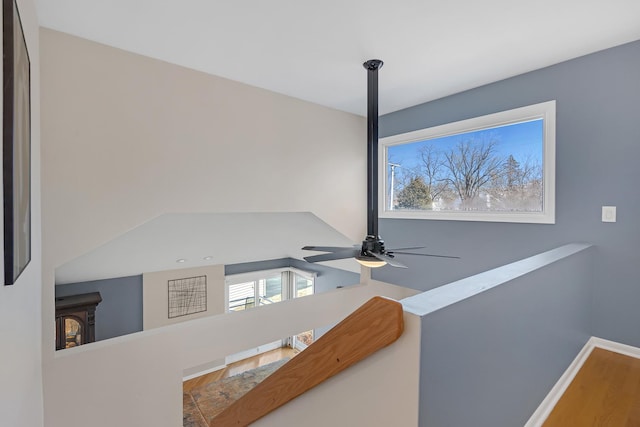 interior details with ceiling fan, a wood stove, and baseboards