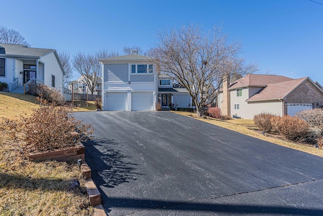 view of front facade with a garage, a residential view, and aphalt driveway