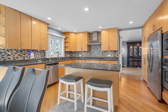 kitchen with a kitchen island, open shelves, stainless steel appliances, wall chimney exhaust hood, and light wood-type flooring