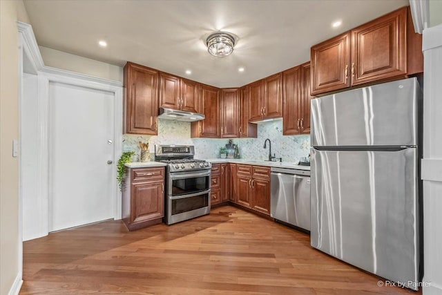 924 Colony Lake Dr, Schaumburg, IL 60194 - kitchen featuring appliances with stainless steel finishes, under cabinet range hood, light wood-style flooring, light countertops, and backsplash