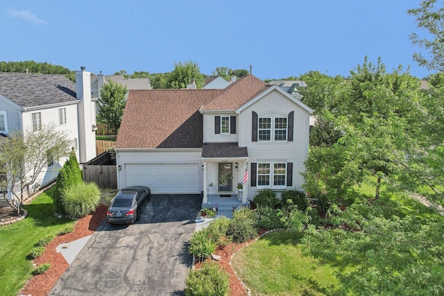 traditional-style house with a garage, aphalt driveway, roof with shingles, and fence