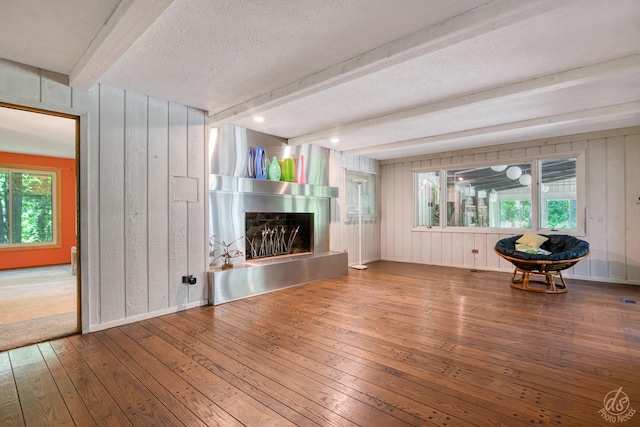 14930 W Wadsworth Rd, Wadsworth, IL 60083 - unfurnished living room with wood-type flooring, a fireplace with raised hearth, beamed ceiling, a textured ceiling, and wooden walls