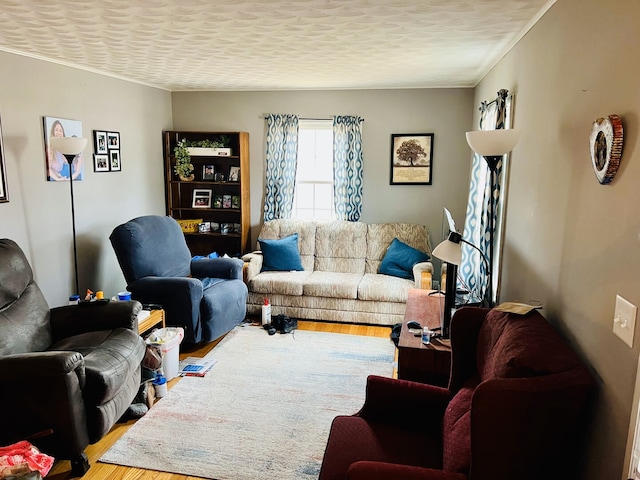 living room featuring a textured ceiling, ornamental molding, and wood finished floors