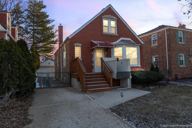 view of front of house with a gate, a chimney, and brick siding