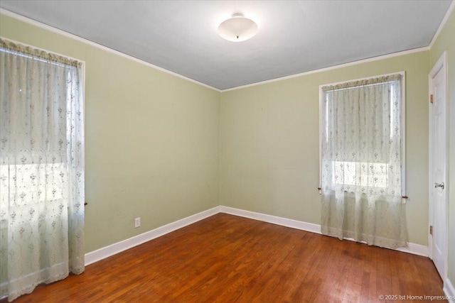 empty room with crown molding, baseboards, and wood finished floors