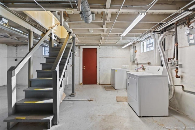 basement featuring electric panel, stairway, and washing machine and clothes dryer