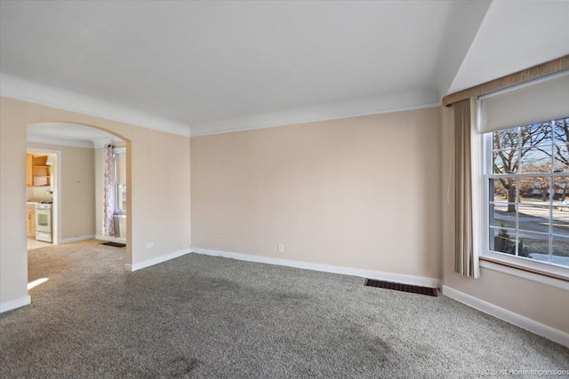 carpeted spare room with arched walkways, visible vents, crown molding, and baseboards