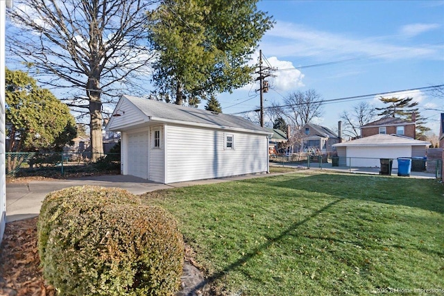 detached garage featuring concrete driveway and fence