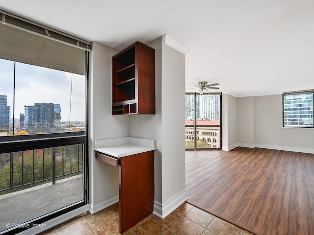 kitchen featuring plenty of natural light, a ceiling fan, baseboards, light countertops, and expansive windows