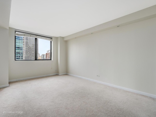 empty room featuring light carpet and baseboards