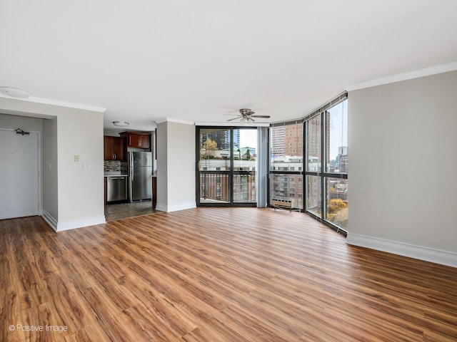 unfurnished living room with crown molding, floor to ceiling windows, a ceiling fan, light wood-type flooring, and baseboards