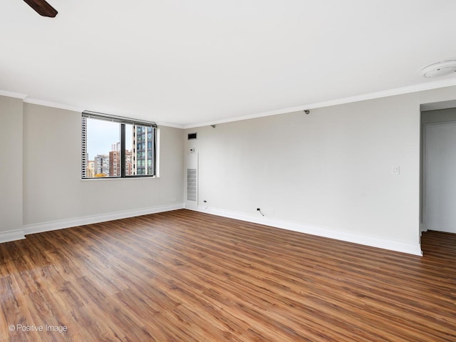 unfurnished room with wood finished floors, baseboards, ornamental molding, and a smoke detector