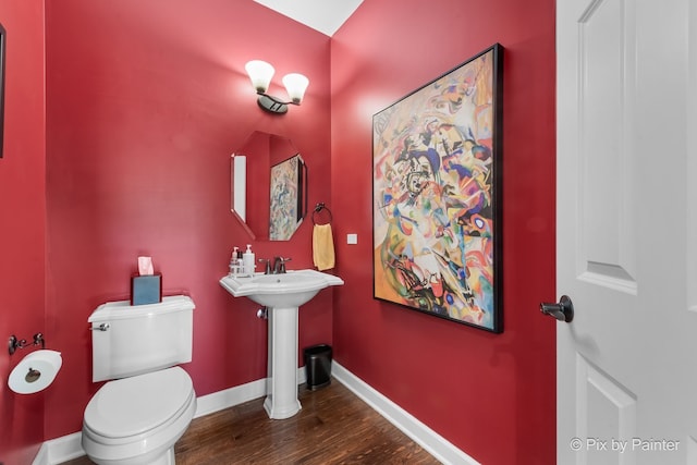 half bathroom featuring toilet, baseboards, and wood finished floors