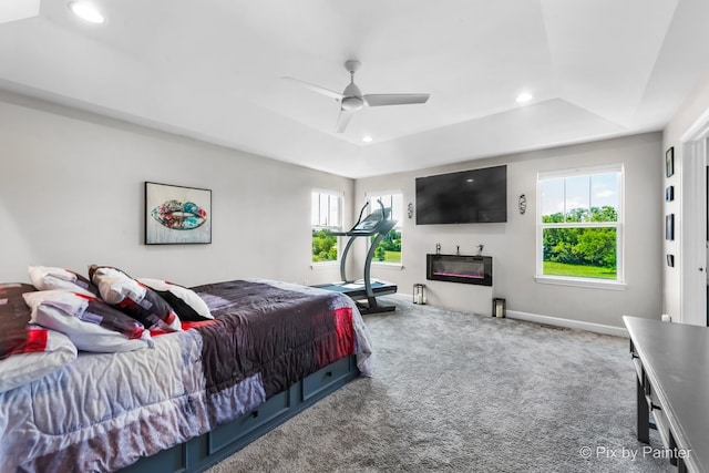 carpeted bedroom with multiple windows, a raised ceiling, and recessed lighting