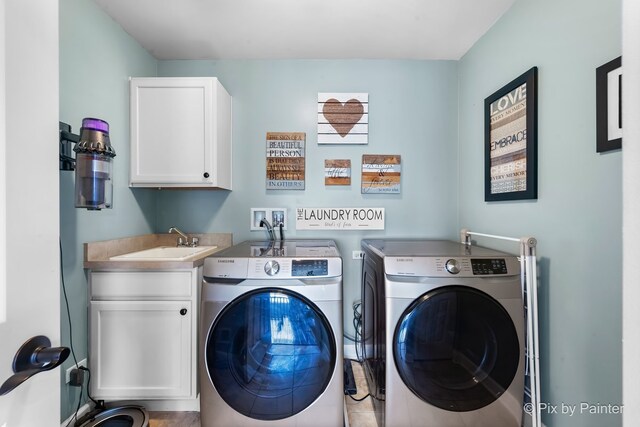 clothes washing area featuring cabinet space, washer and clothes dryer, and a sink