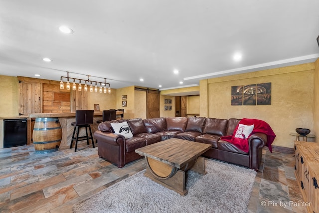 living room featuring a barn door, indoor bar, stone tile flooring, and recessed lighting