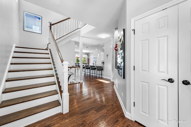 foyer featuring stairway, dark wood-style flooring, and baseboards