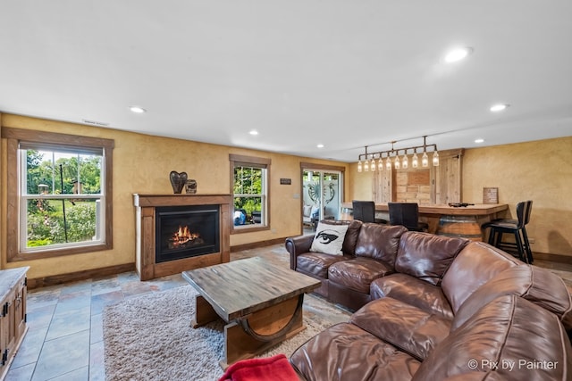 living area featuring a lit fireplace, visible vents, baseboards, and recessed lighting