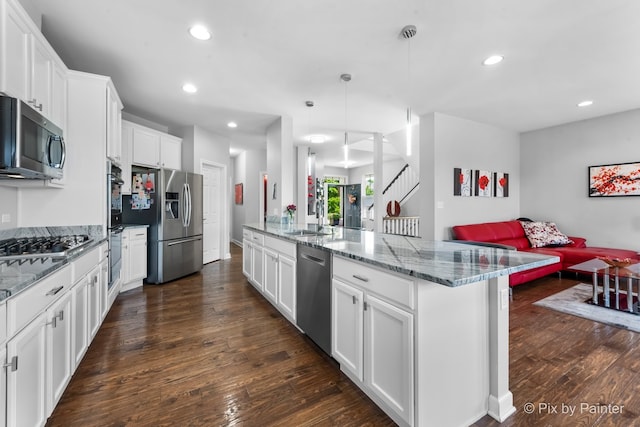 kitchen with dark wood-style floors, appliances with stainless steel finishes, open floor plan, white cabinetry, and a sink