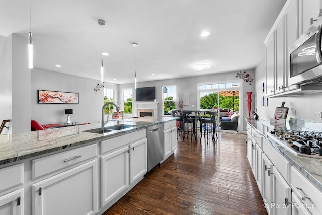 kitchen featuring dark wood-style floors, appliances with stainless steel finishes, white cabinets, and a sink