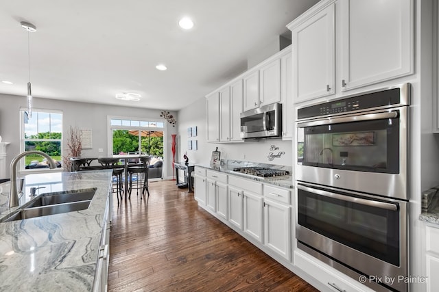 kitchen with recessed lighting, stainless steel appliances, a sink, white cabinets, and dark wood finished floors