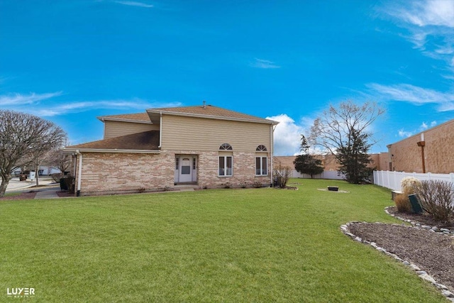 back of property featuring brick siding, a yard, and fence