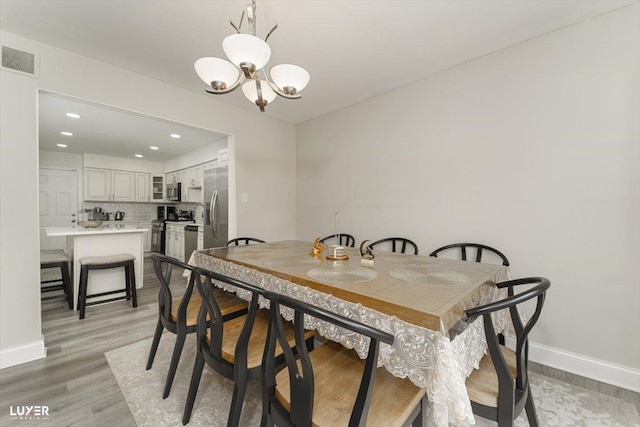 dining room featuring baseboards, visible vents, light wood-type flooring, a notable chandelier, and recessed lighting