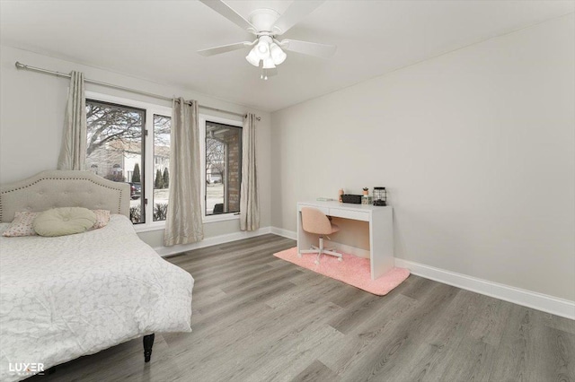 bedroom featuring wood finished floors, a ceiling fan, and baseboards