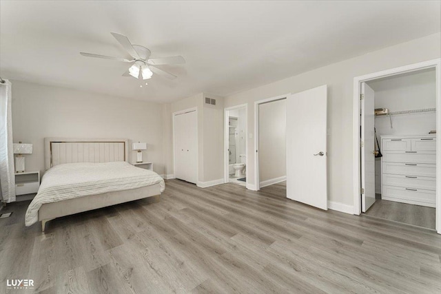 bedroom featuring visible vents, baseboards, wood finished floors, and ensuite bathroom