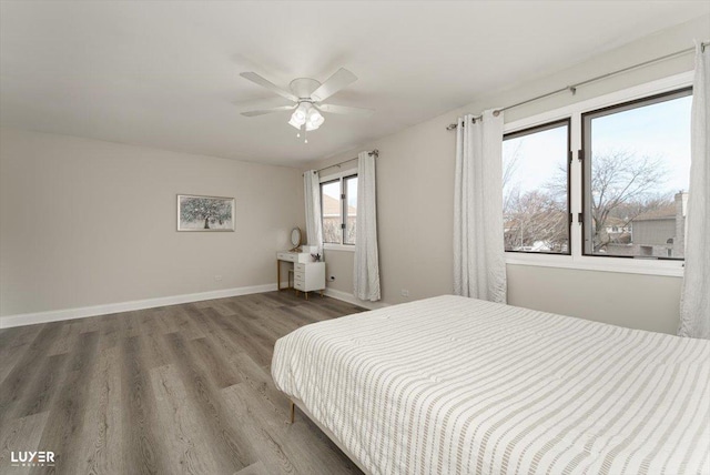 bedroom with a ceiling fan, baseboards, and wood finished floors