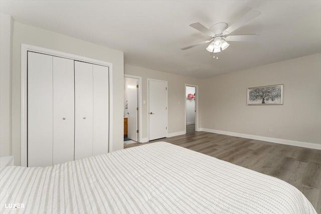 bedroom with a closet, wood finished floors, a ceiling fan, and baseboards