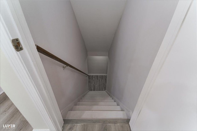 stairway with wood finished floors and baseboards