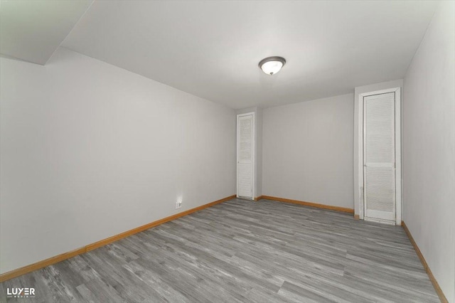 spare room featuring baseboards and wood finished floors