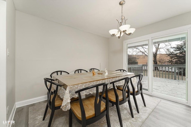 dining space featuring light wood-type flooring, baseboards, and a chandelier