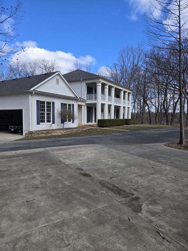 exterior space featuring a garage, roof with shingles, and a balcony