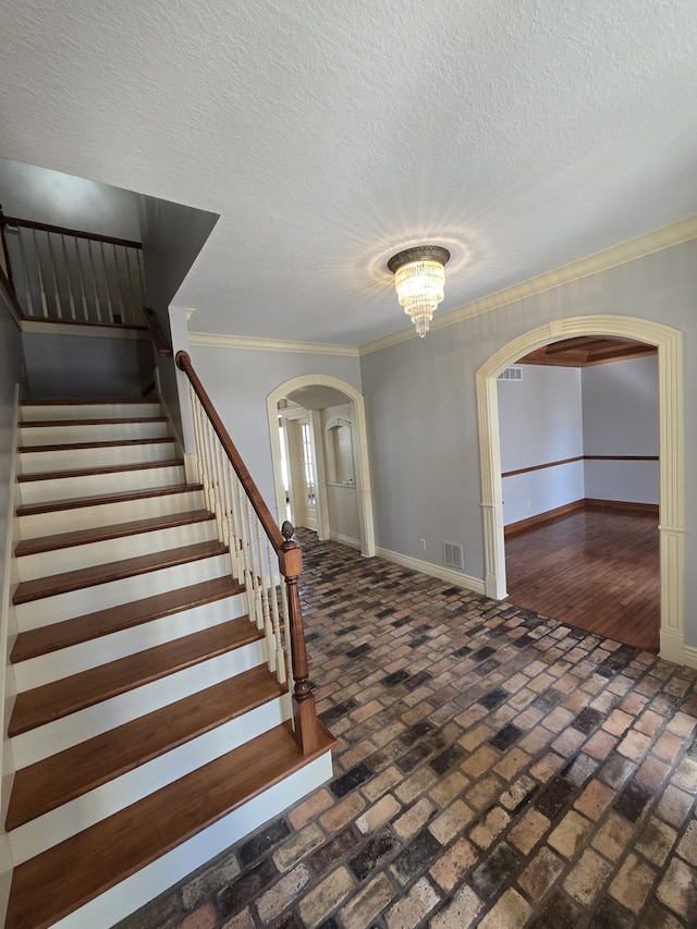 entryway featuring arched walkways, brick floor, visible vents, and baseboards