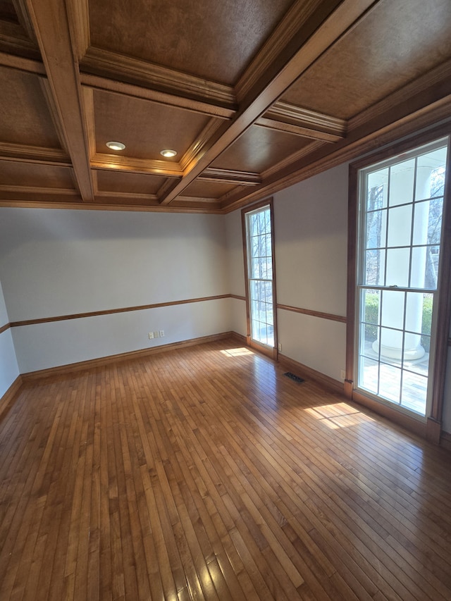 unfurnished room with baseboards, visible vents, and hardwood / wood-style floors