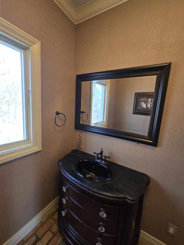 bathroom with brick floor, crown molding, vanity, and baseboards