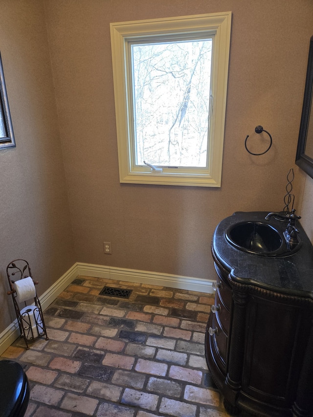 interior space featuring brick floor, baseboards, and vanity