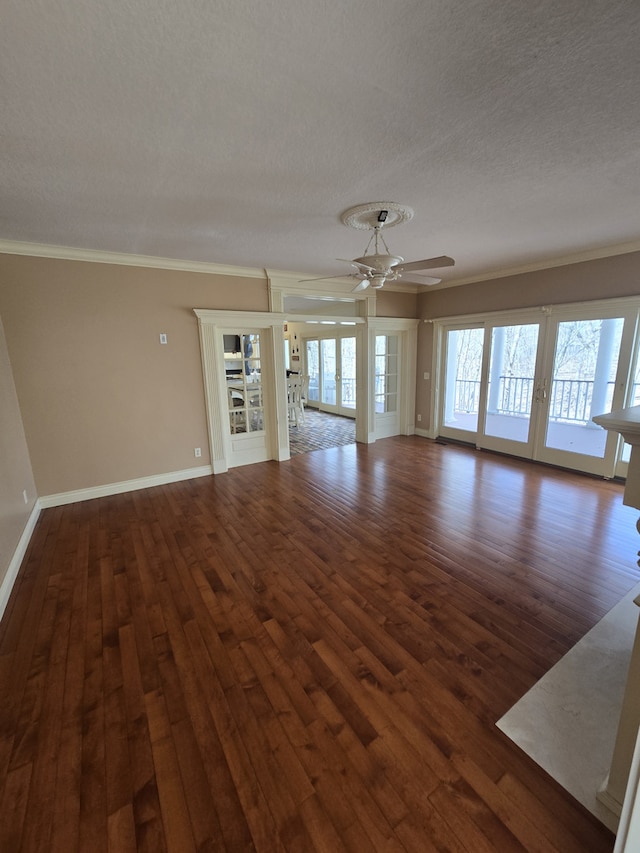 empty room with ceiling fan, a textured ceiling, dark wood-style flooring, baseboards, and crown molding