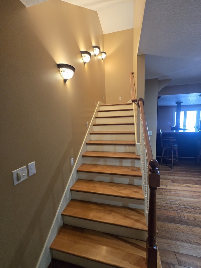 staircase with baseboards and wood finished floors