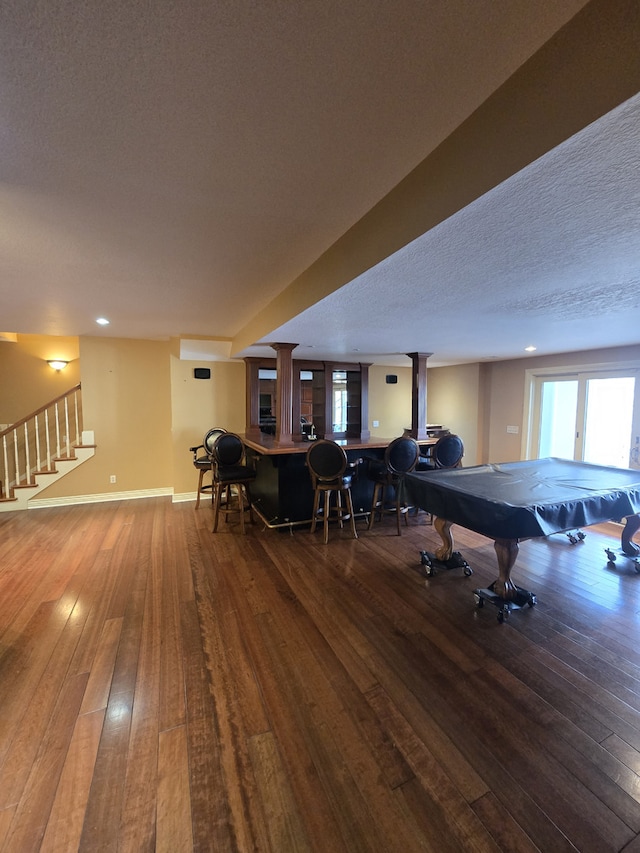 rec room with a dry bar, billiards, baseboards, hardwood / wood-style floors, and a textured ceiling